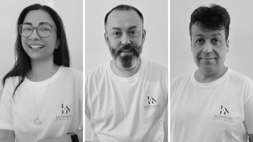 Schwarzweiß-Gruppenbild des heySimeon Teams mit drei Mitarbeitenden in weißen T-Shirts